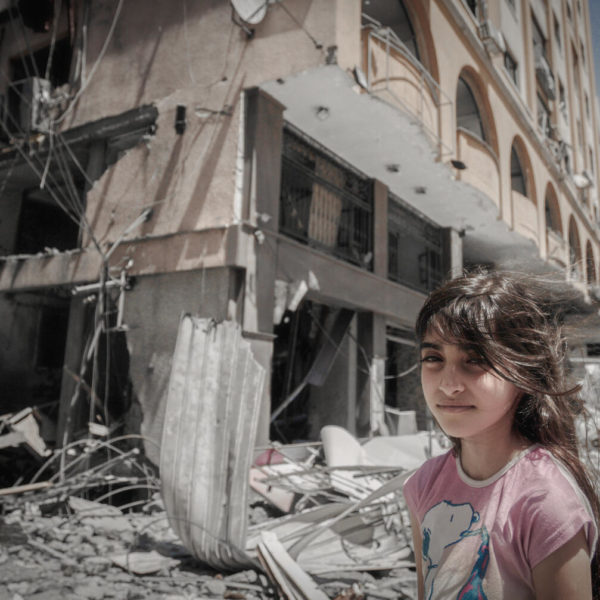 A Palestinian girl standing in front of her damaged home in Gaza City.