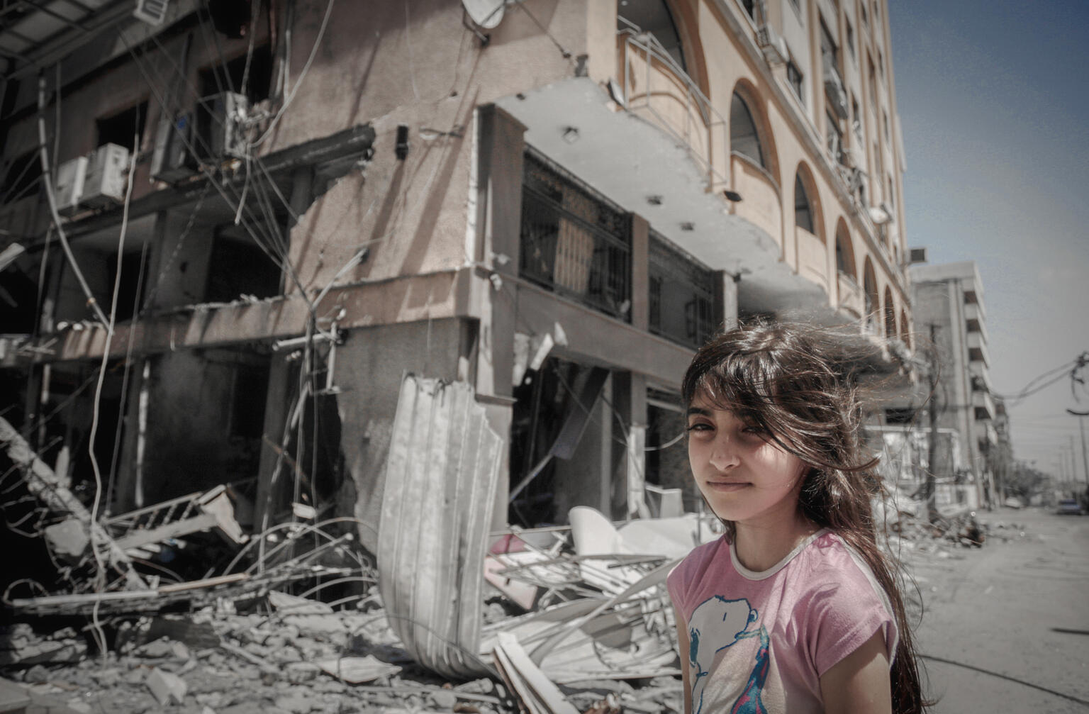 A Palestinian girl standing in front of her damaged home in Gaza City.