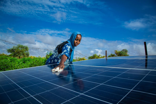 Woman wiping down a large solar panel.