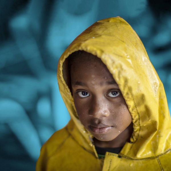 Young child wearing a yellow raincoat.