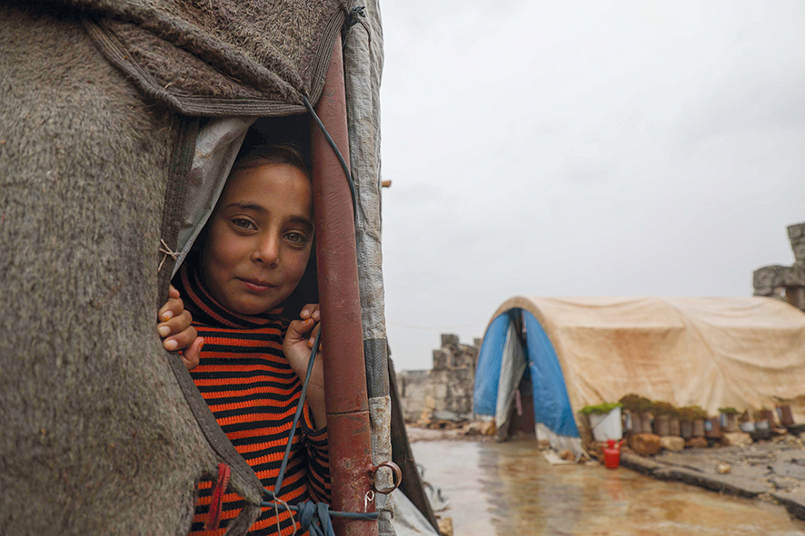Boy at a flooded camp for people displaced by conflict in Syria