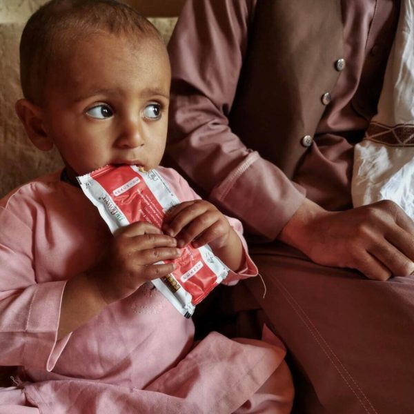 A young child eats a nutritional pack.