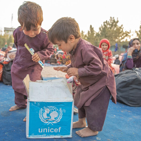 Two children peer inside a water and hygiene kit.