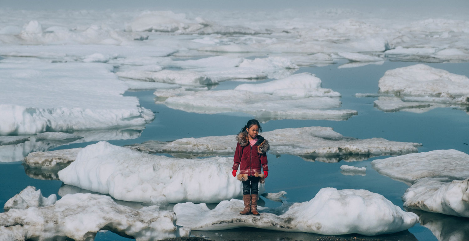 A girl stands on an ice floe on a shore of the Arctic Ocean in Barrow, Alaska.