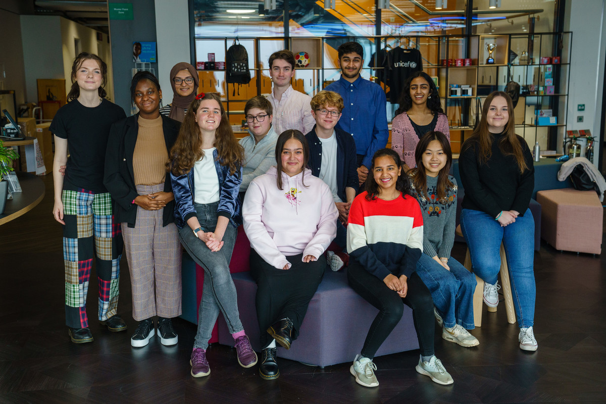 A group of 13 young people pose for a group photograph in the UNICEF UK reception area