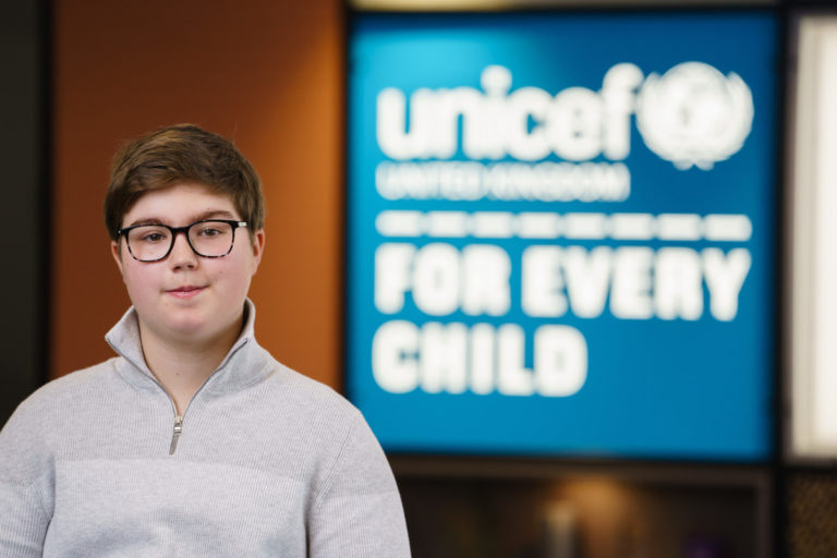 Arthur poses for a photograph in front of the UNICEF UK sign.