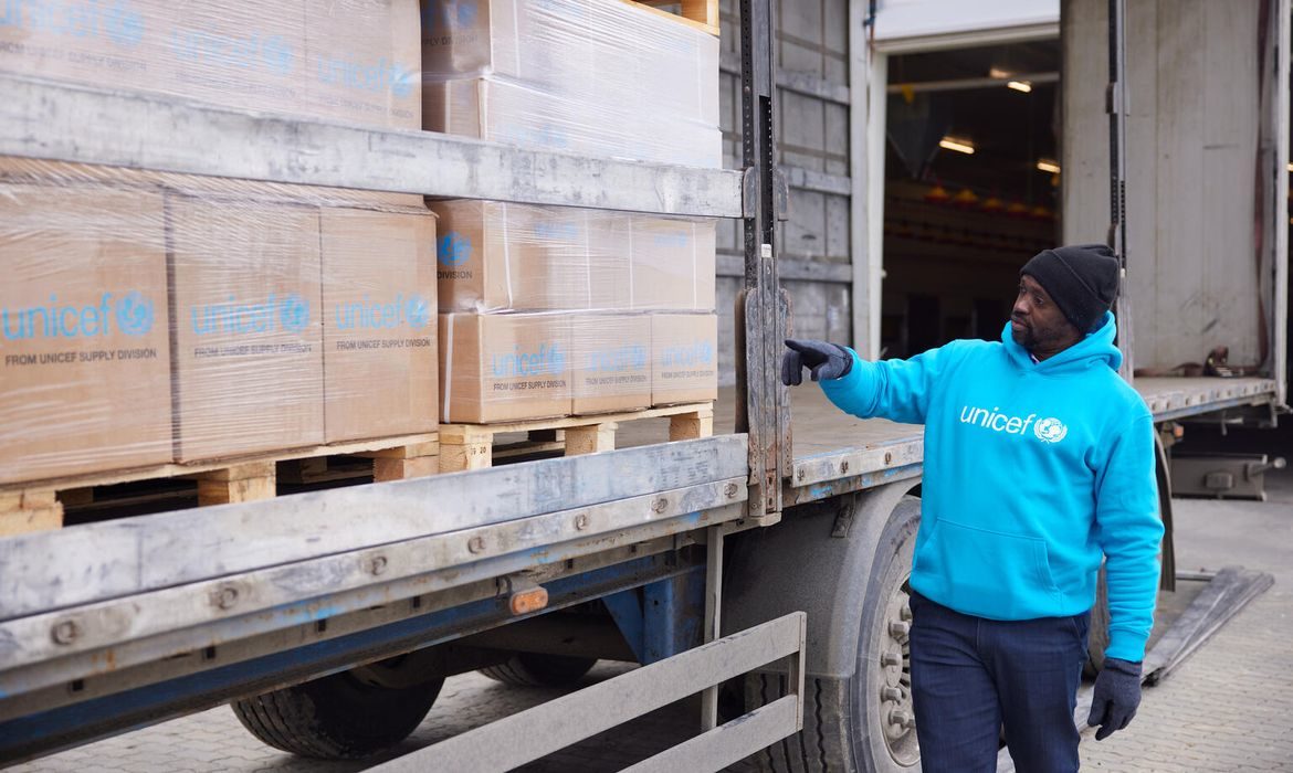 UNICEF staff member next to boxes of supplies on a lorry