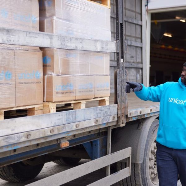 UNICEF staff member next to boxes of supplies on a lorry