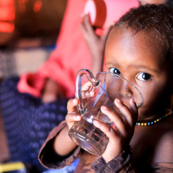 A 2 years old drinks water inside his home in Somalia.