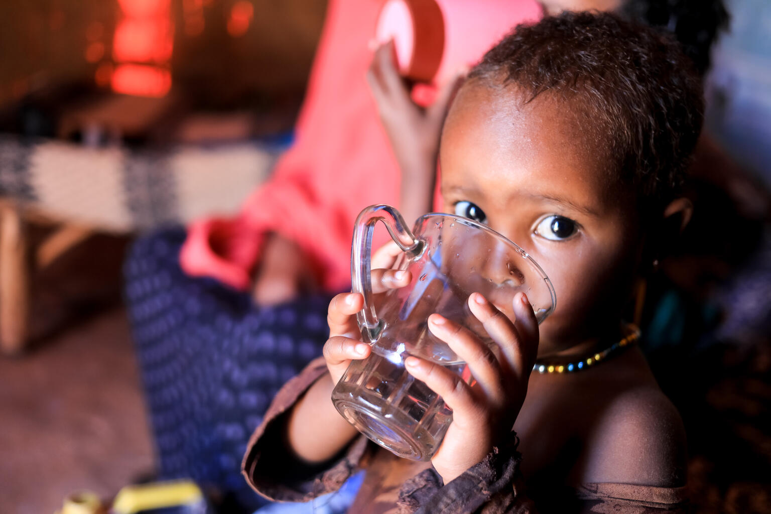 Hibo, 2 years old drinks water inside his home in Somalia. East Africa Crisis