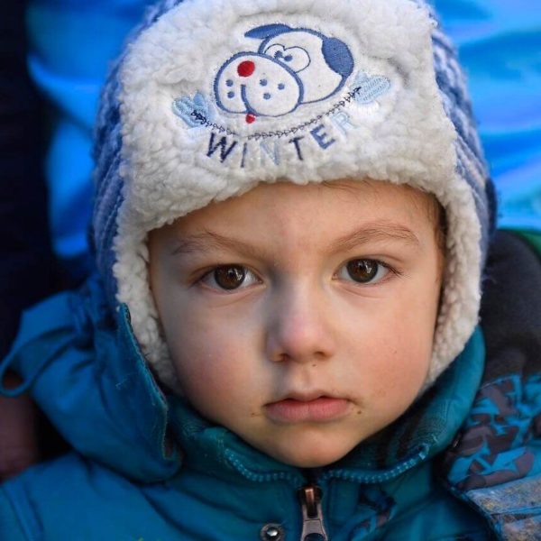 Young child from Ukraine wearing a fleece-lined hat