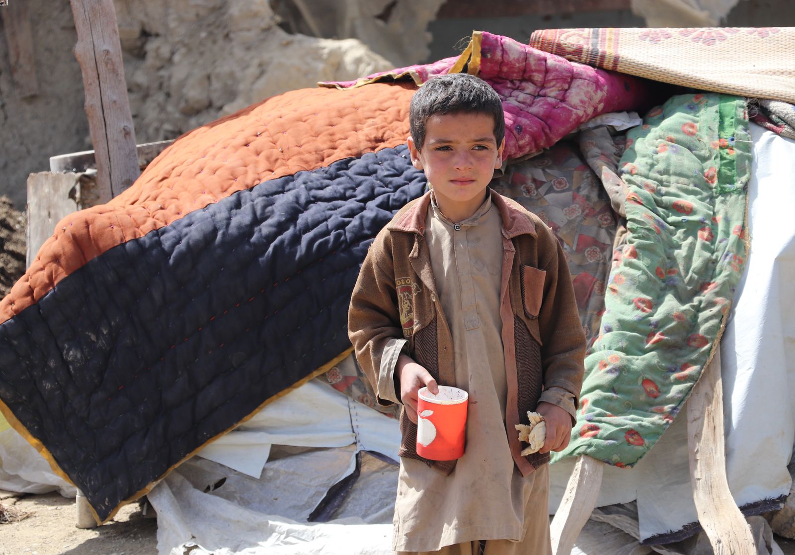 Halim, 8, from Gayan Village, Paktika Province standing in the street in front of a makeshift shelter following the Afghanistan earthquake.