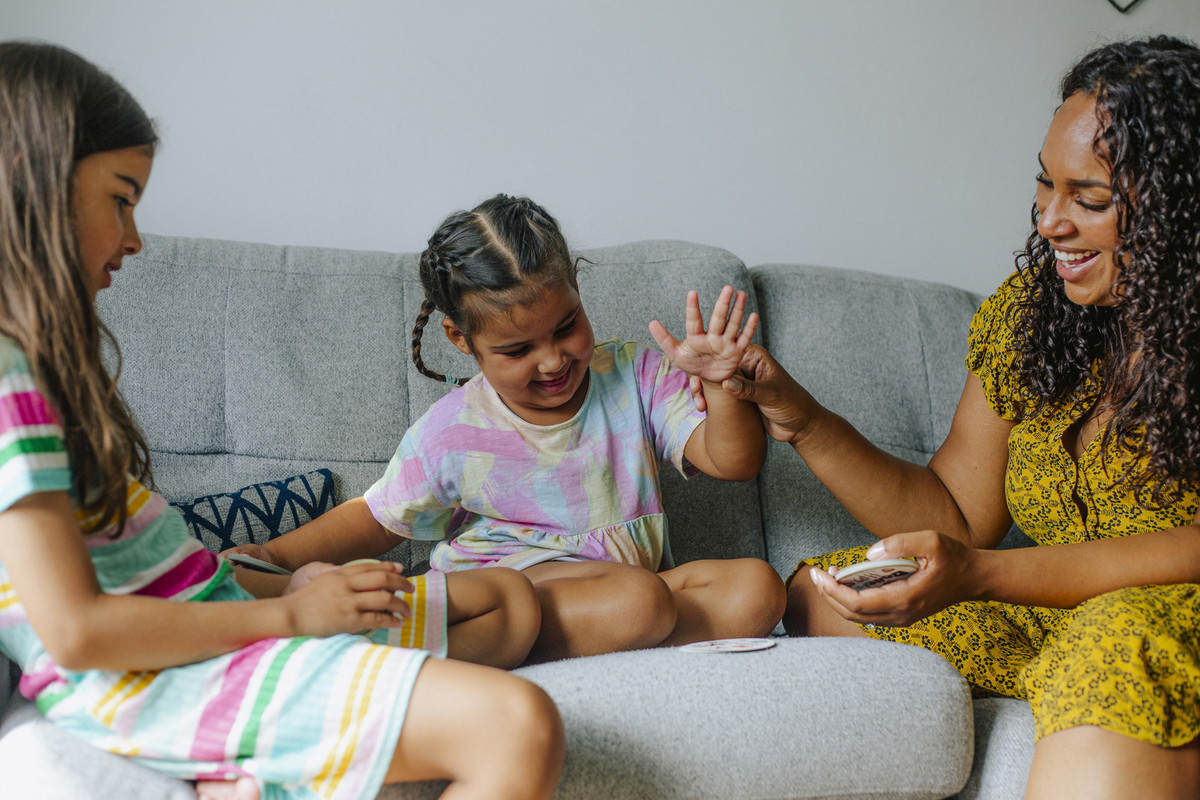 Jocelyn and her daughters play a card game at their home, England, August 2022.
