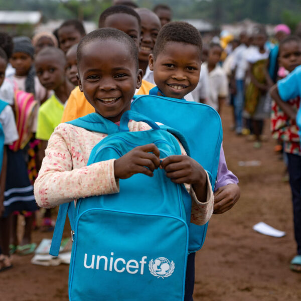 Young boy looking into the camera, smiling and holding a UNICEF bag