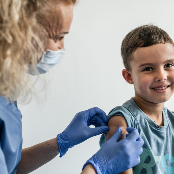 Mykyta smiles as he receives his vaccine shot by Nurse Ewelina Tytula on his right arm.