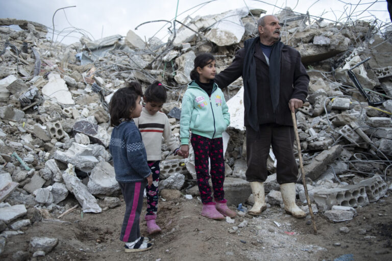 Family in northwestern Syria stands in front of rubble after the turkiye-syria earthquakes.