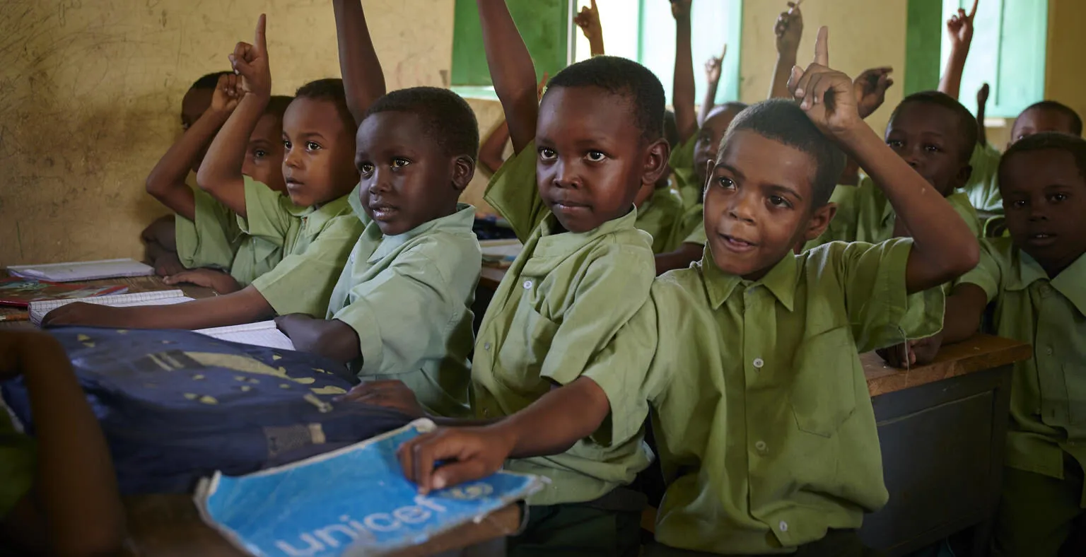 Children raising their hands to answer a question from a teacher.