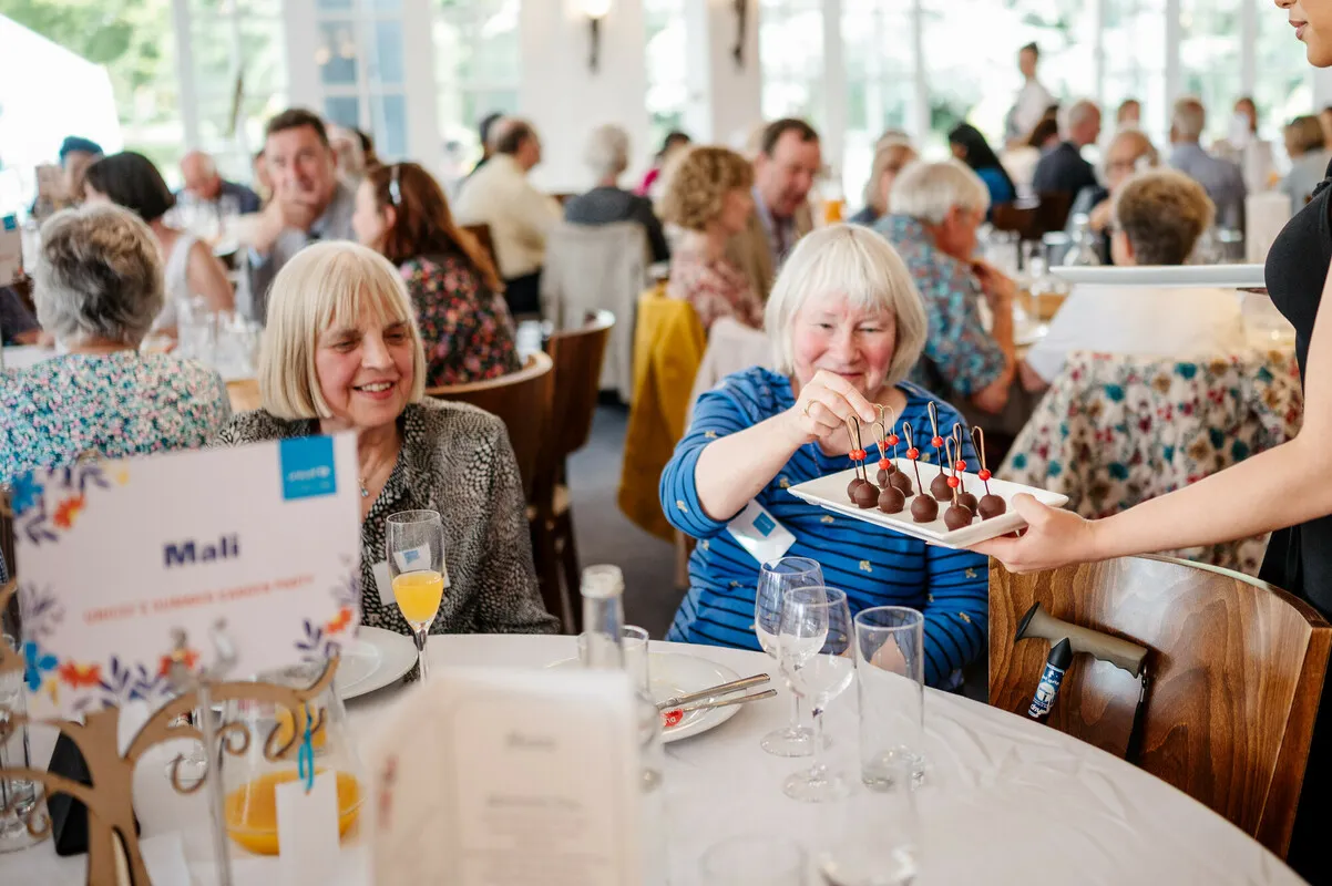 Group of people gathered together enjoying food.