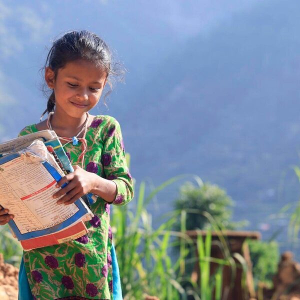 8-year-old holds her books, just retrieved from the rubble of her earthquake-hit home.