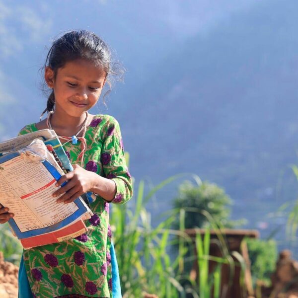 8-year-old holds her books, just retrieved from the rubble of her earthquake-hit home.