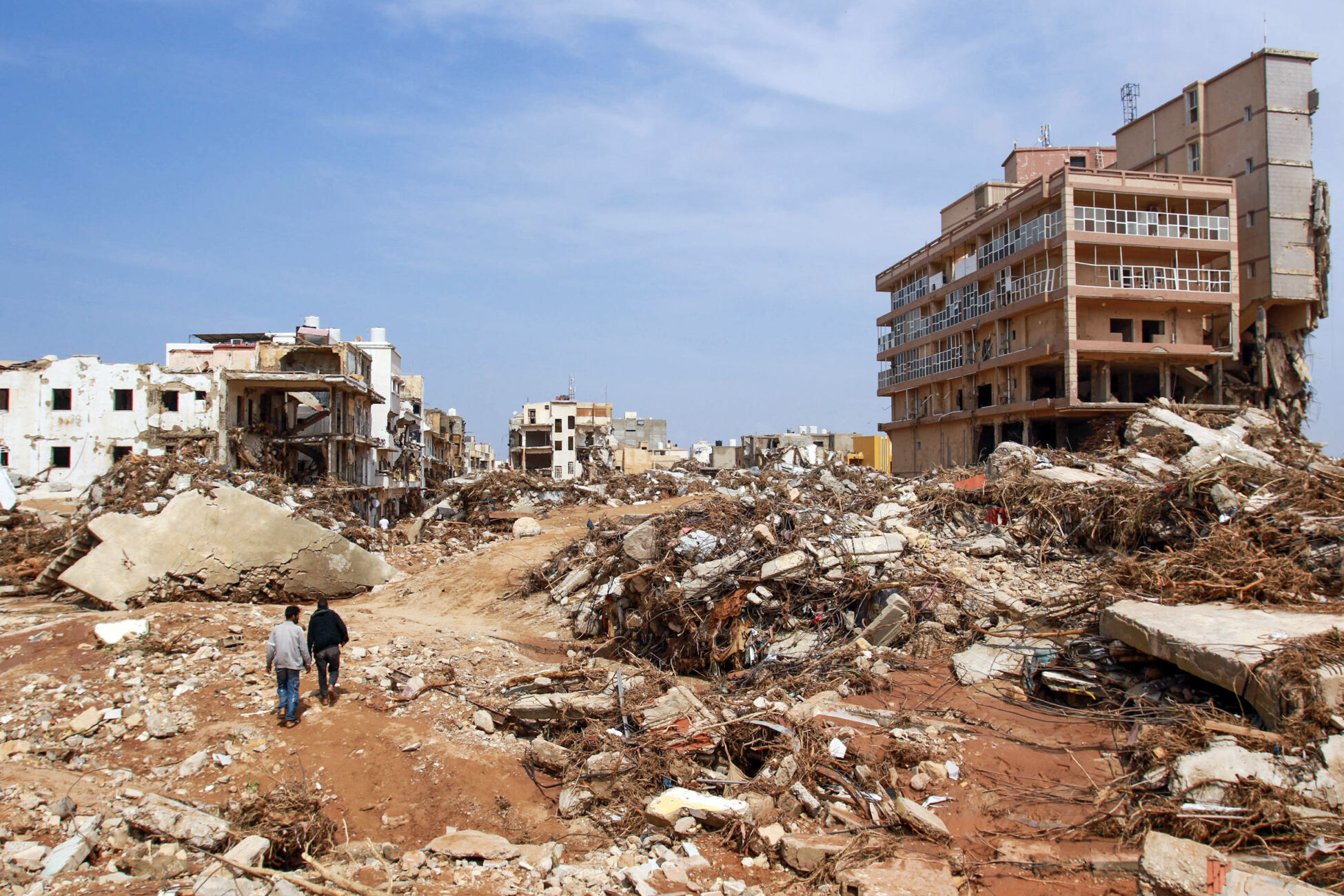 Men walk past debris of buildings caused by flash floods in Derna, eastern Libya, on September 11, 2023.