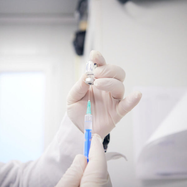 Close-up of a doctor's hands preparing a vaccine does in a needle.