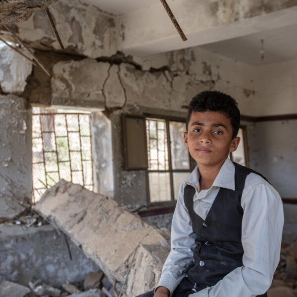 12-year-old Ahmed sits on the rubble of his school.