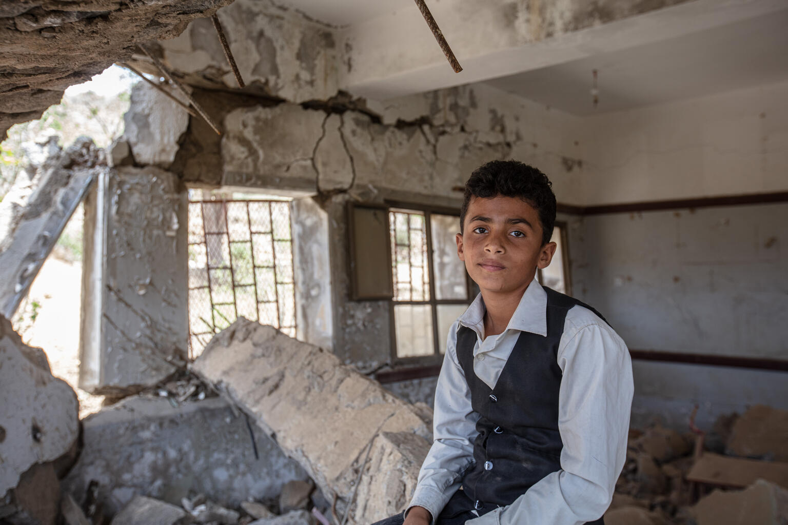 12-year-old Ahmed sits on the rubble of his school.