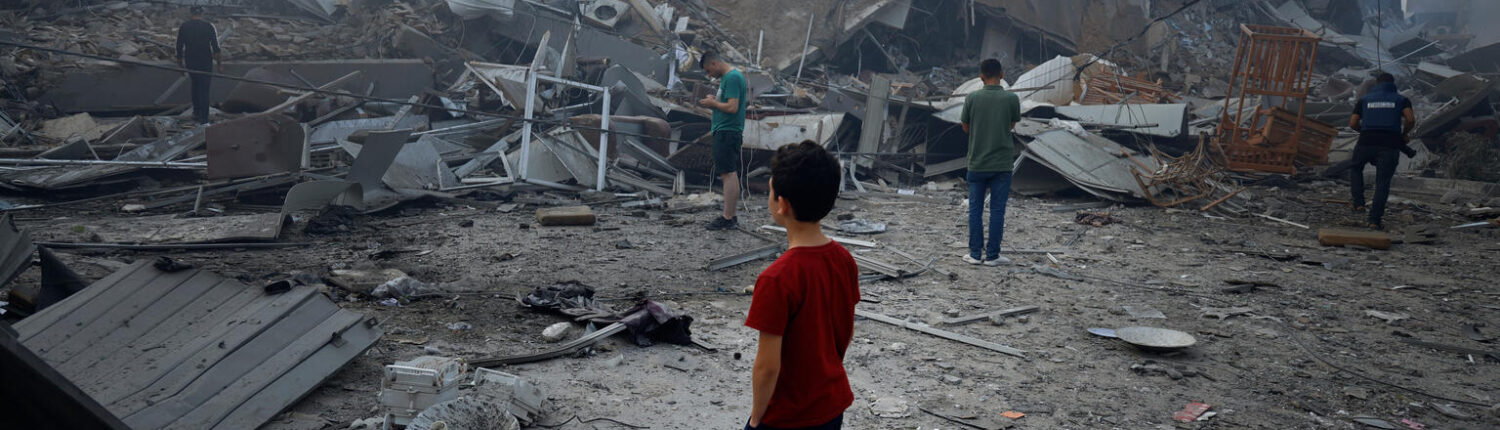 A young boy looks at the devastation of his bombed neighbourhood.