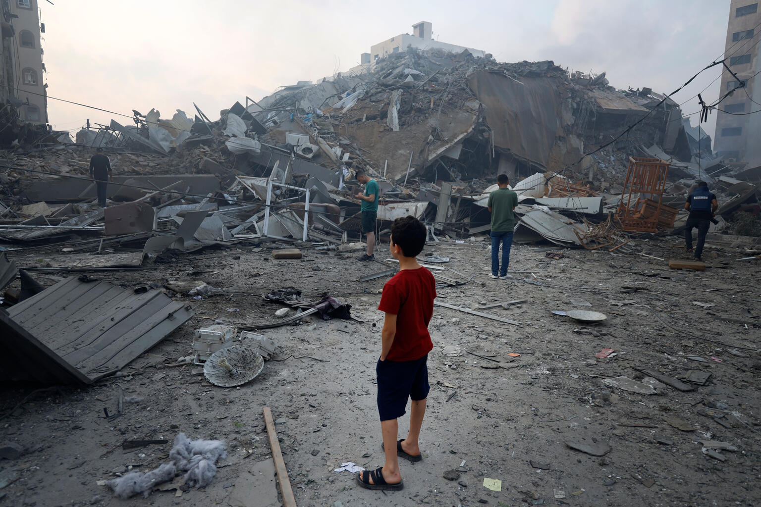 A young boy looks at the devastation of his bombed neighbourhood.