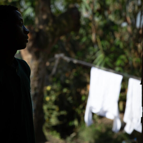 A boy is standing at a doorway looking outside.