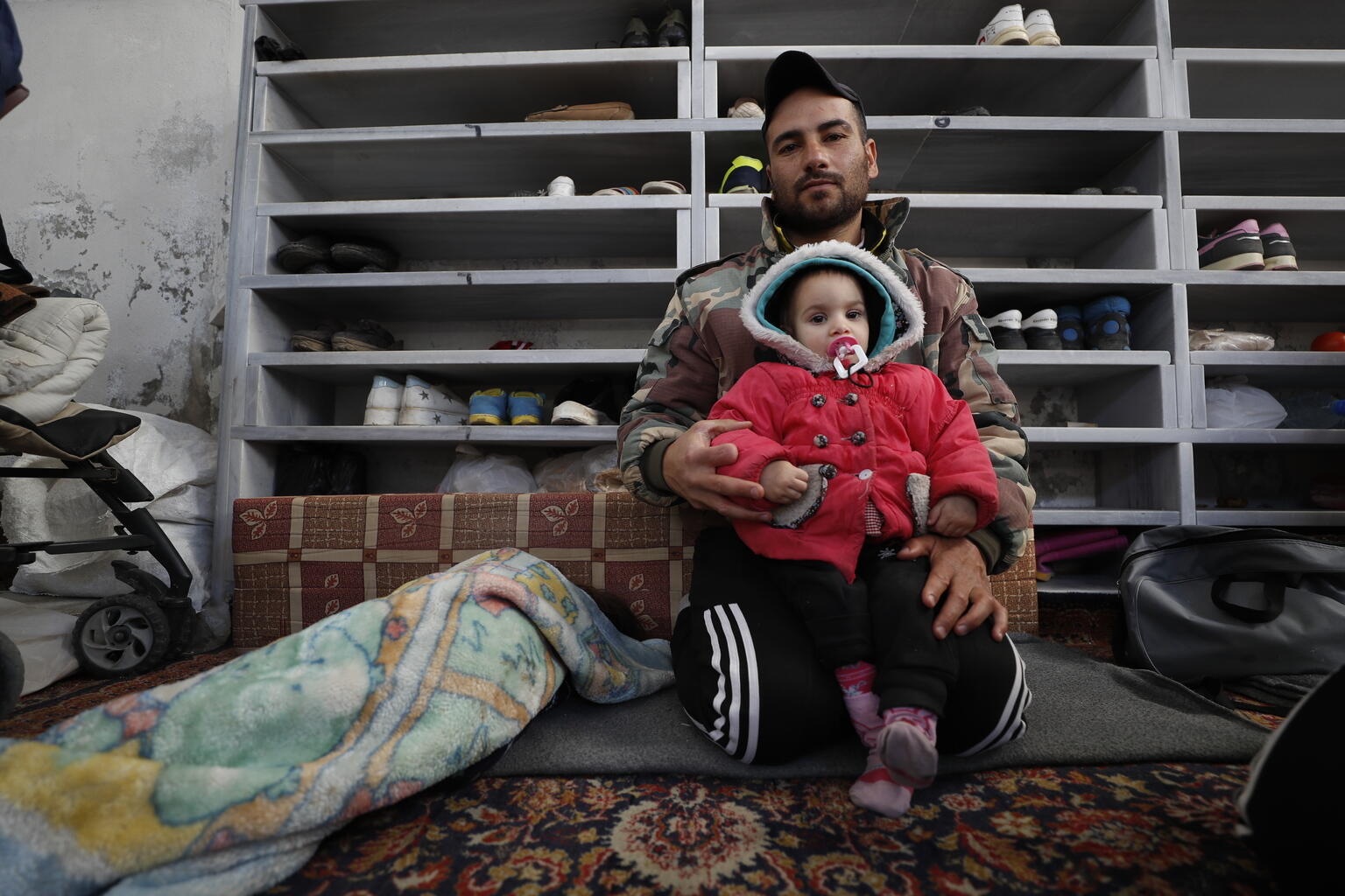 A man sits with his young daughter in a temporary shelter in Al-Mansory Mosque in the old city of Jableh district, northwestern Syria.