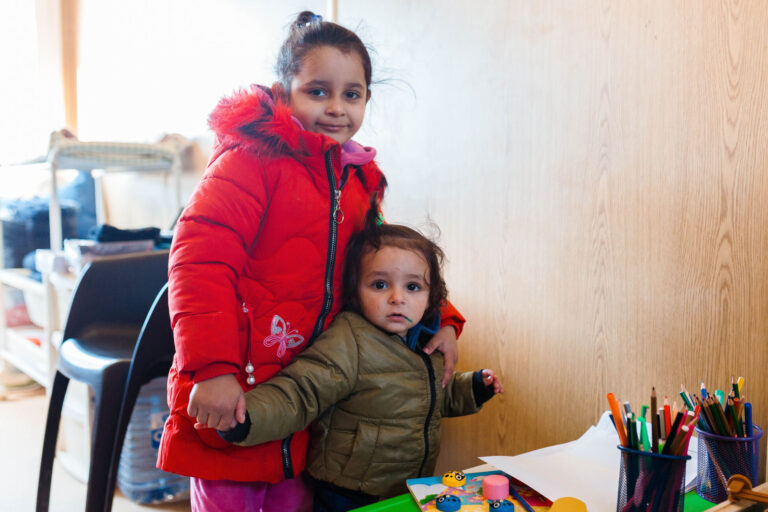 Two girls under 5 smile at a UNICEF-funded blue dot centre on the border of Ukraine and Moldova.