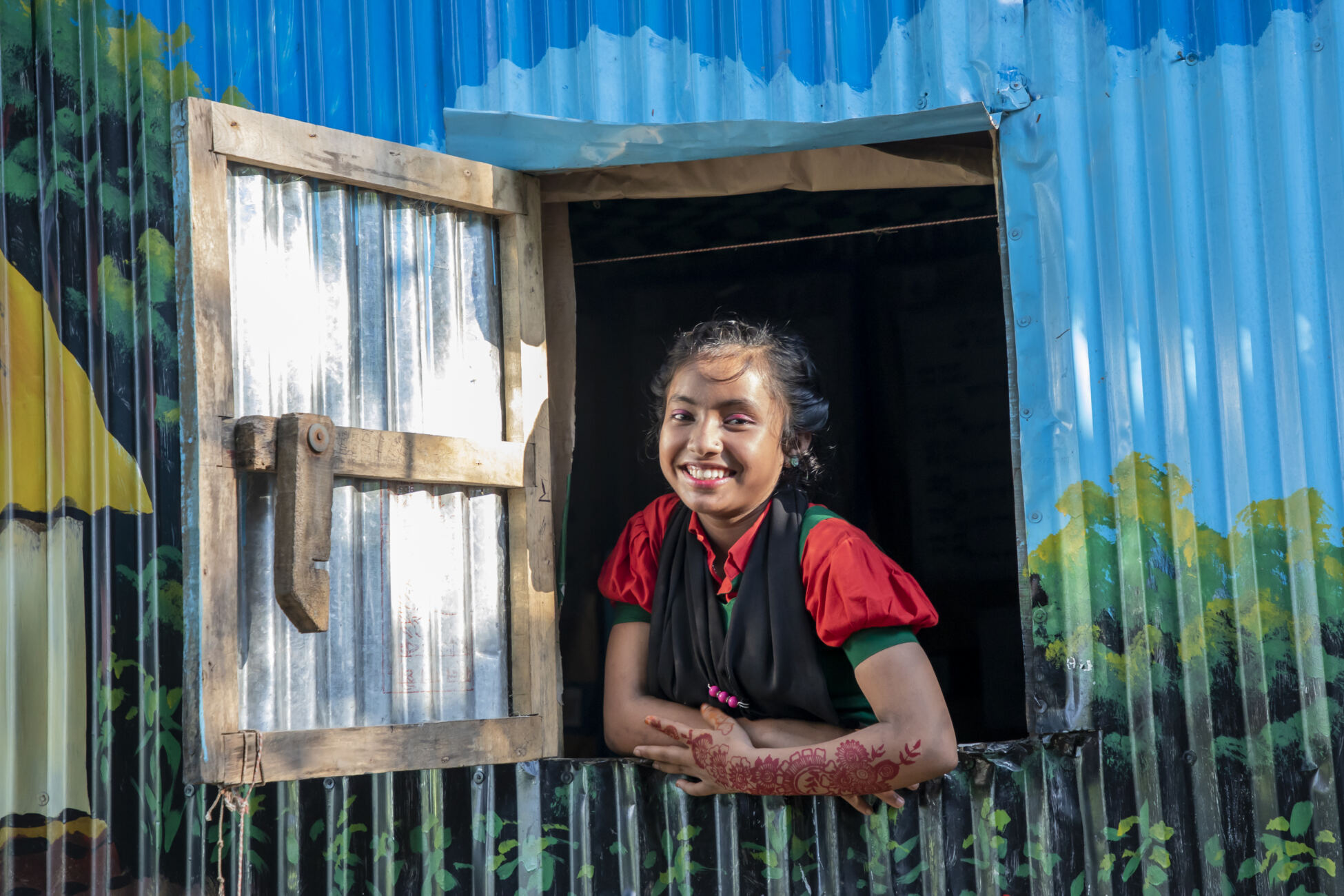 A 15 year old girl smiles out of a classroom window in Sylhet, Bangladesh.