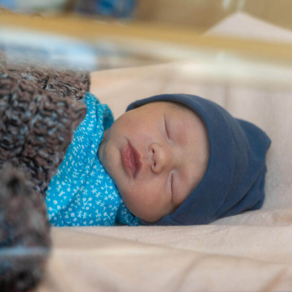 A newborn baby girl wrapped up is lying in a cradle.