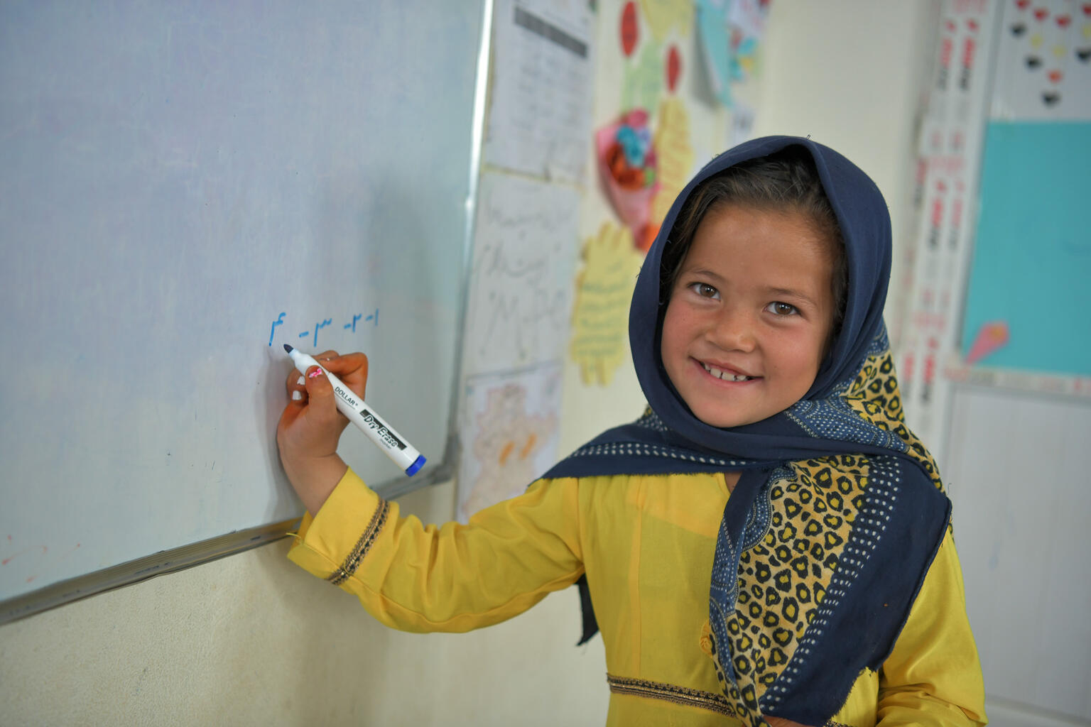6-year-old Najma practices writing math problems on a whiteboard in Afghanistan