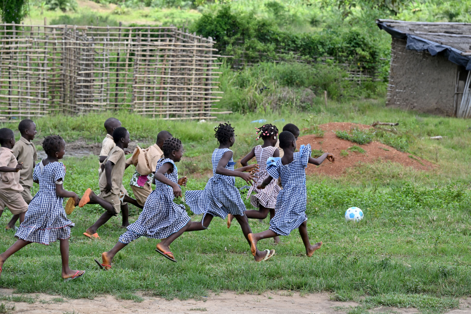 A group of children chase after a football in their school playground.