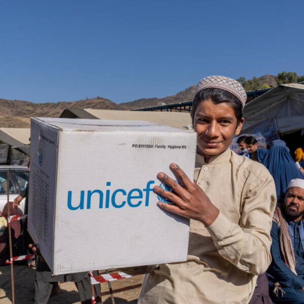 A young man carries a UNICEF-branded emergency box.