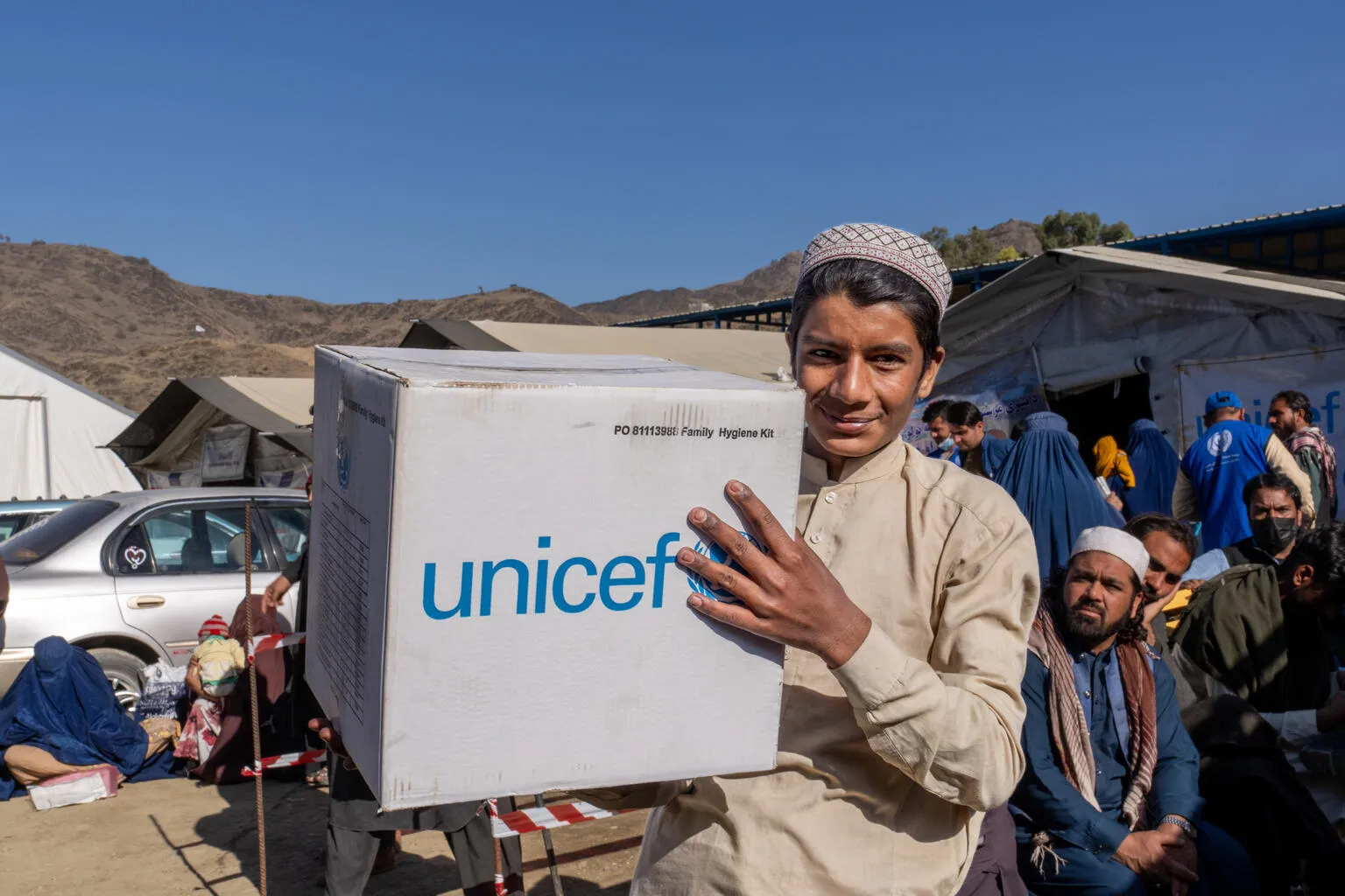 A young man carries a UNICEF-branded emergency box.