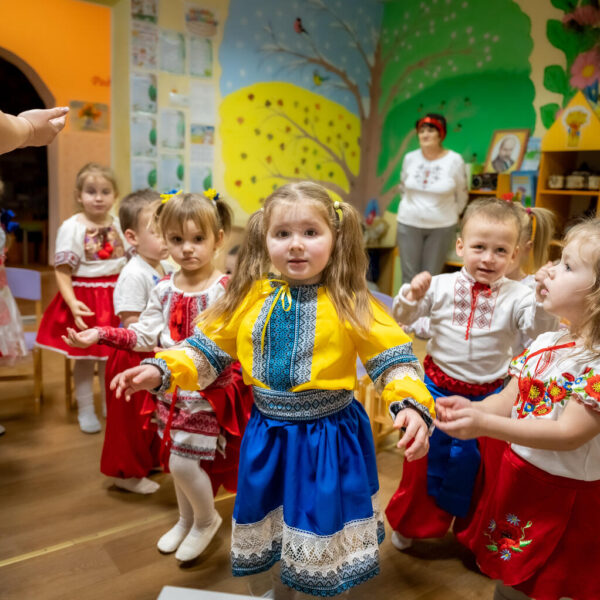 A group of young children learn to dance in traditional Ukrainian clothing.