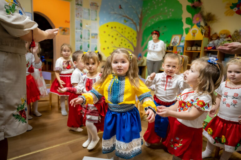 A group of young children learn to dance in traditional Ukrainian clothing.