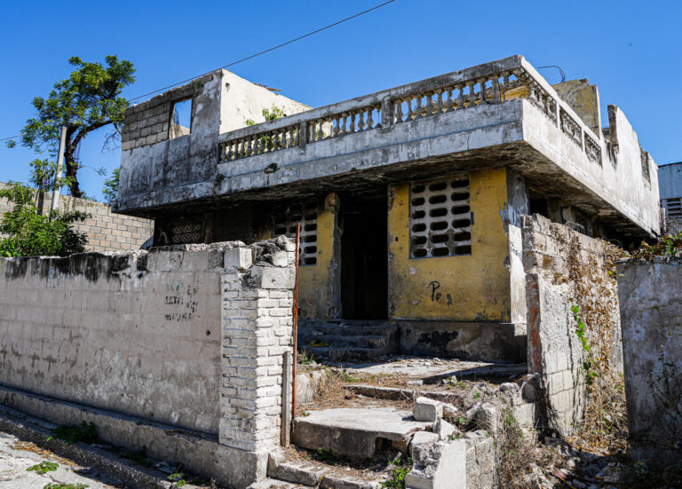 A weathered house in Haiti without a door or glass in the windows.