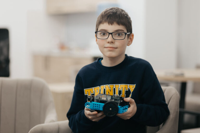 10-year-old Miroslav holds a small, wheeled robot in his hands.