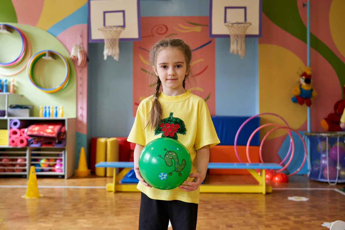 Emiliya, 6, holds a rubber ball in a school gym.