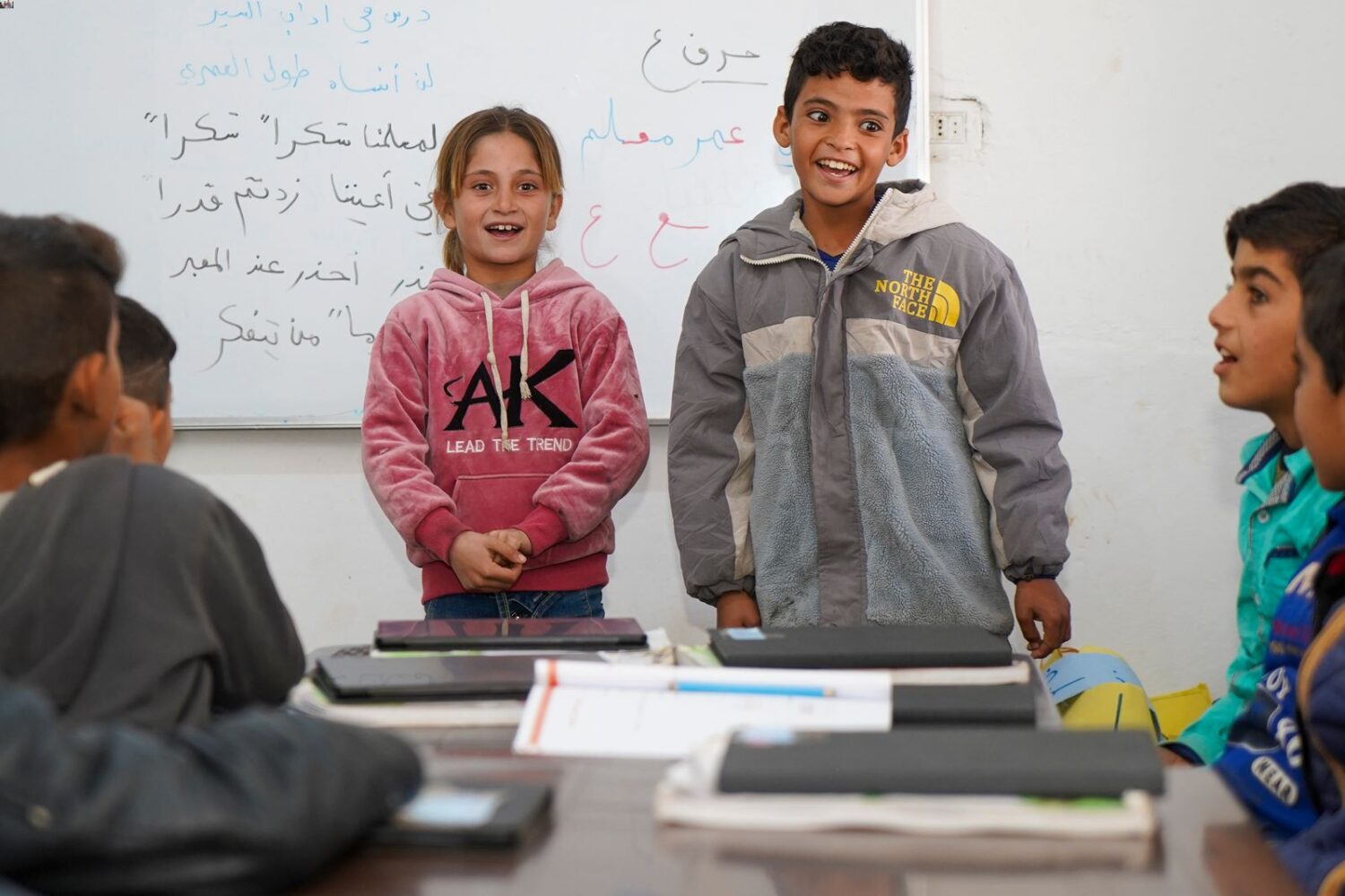 Children in Northeast Syria present in front of a class where the children learn on tablets, which offer a more accessible way of learning.