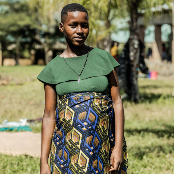 A pregnant person stands in a grassy area.