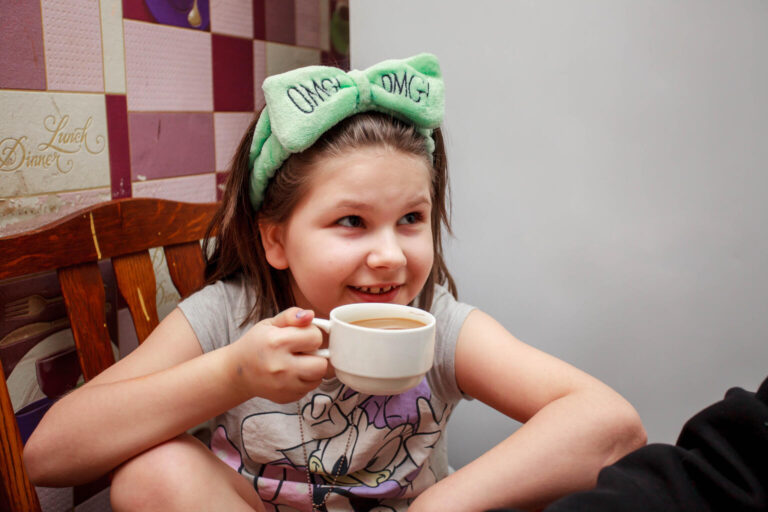 8-year-old Stefania drinks tea at the table.