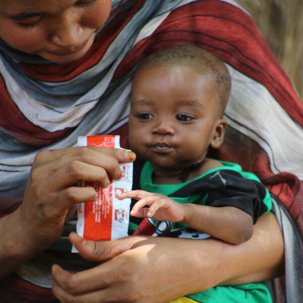 A mother feeds her 6-month-old child with ready-to-use-therapeutic food (RUTF) at their home in Sudan.