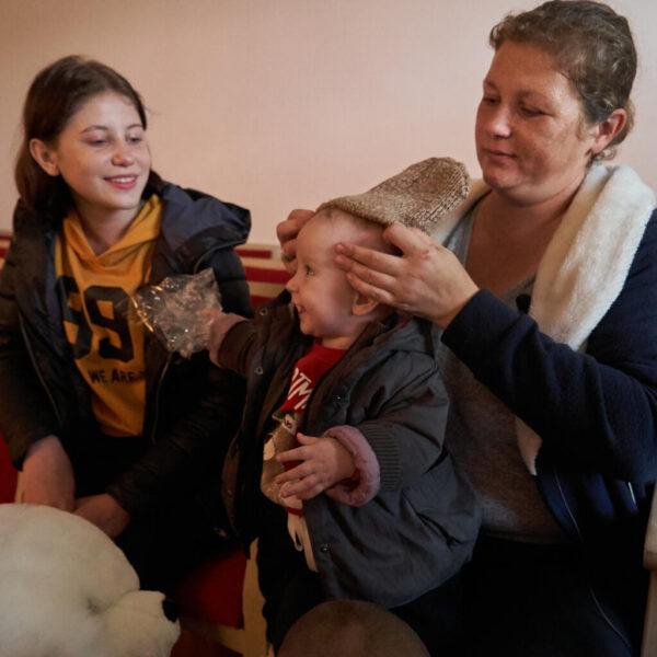 A mother puts a warm hat on her 10-month-old child.