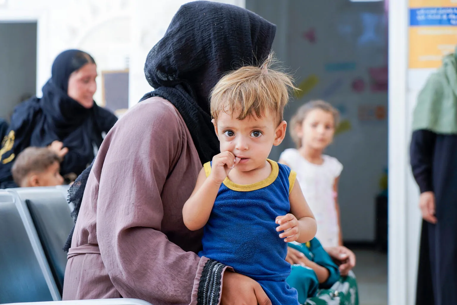 A mother is seated with her son, waiting at a UNICEF supported clinic in Syria.